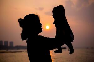 silueta de madre obras de teatro con su niñito en contra el puesta de sol. foto