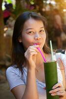 joven hermosa asiático mujer Bebiendo roselle jugo en un taza hecho de bambú foto