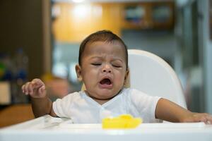 uno asiático bebé llorando en comida silla foto