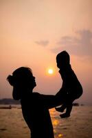 silueta de madre obras de teatro con su niñito en contra el puesta de sol. foto