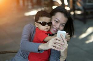 Focus of Asian mother hand and son taking selfie photograph photo