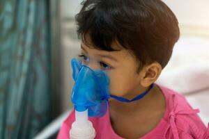 asiático niños chico 3 años antiguo tiene enfermo en nebulizador máscara foto