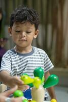 asiático pequeño chico jugando con madera juguetes foto