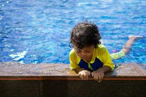 asiático niño chico aprender nadando en un nadando piscina foto
