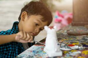 Asian kids enjoying his painting with paintbrush photo