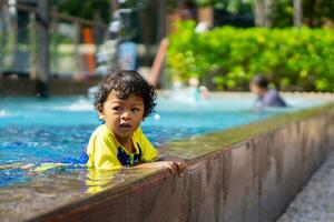 asiático niño chico aprender nadando en un nadando piscina foto