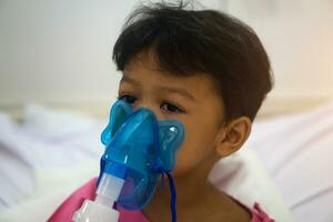 asiático niños chico 3 años antiguo tiene enfermo en nebulizador máscara foto