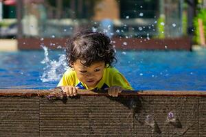 asiático niño chico aprender nadando en un nadando piscina foto