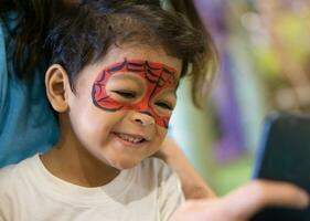 asiático niño chico con pintado cara como un araña foto