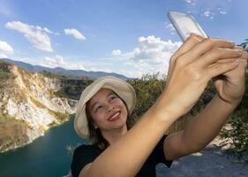 Asian female tourists are taking pictures of themselves at tourist attractions using a smartphone photo