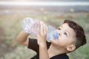 asiático tailandés niños bebida agua en parque foto