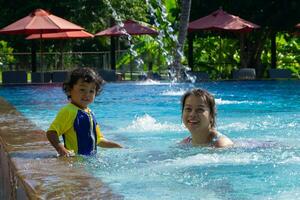 Asian child boy learn swimming in a swimming pool with mom photo