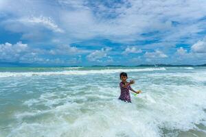 asiático niño jugar en el mar foto