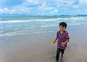 asiático niño jugar corriendo en el playa foto