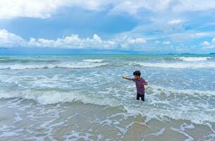 asiático niño disfrutar jugando en el mar foto
