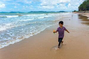 asiático niño jugar corriendo en el playa foto