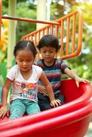 asiático niña y asiático chico es disfrutar en un patio de recreo foto