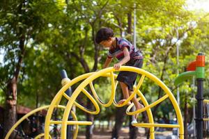 Asian boy is climbing on a playground equipment in a school. photo