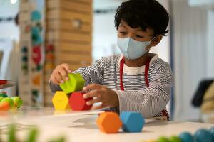 asiático chico vestir cara mascaras a evitar el coronavirus 2019 y jugar juguete en escuelas. foto