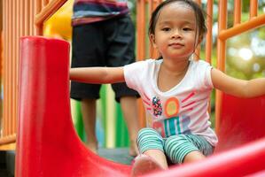 Asian girl is enjoy on a playground equipment in a school. photo