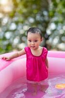 asiático bebé niña jugando en un bebé caucho piscina foto