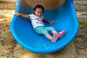 Asian girl is enjoy on a playground equipment in a school. photo