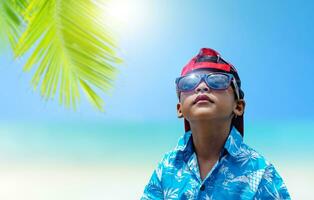 asiático Niños vestir Gafas de sol y verano ropa en un brillante verano mar antecedentes. foto