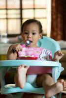 asiático bebé niña 11 meses año antiguo es comiendo alimento. foto