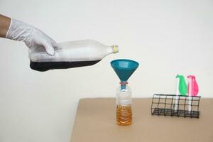 Close up hand holds bottle of soft drinks water to pour into the funnel bottle for doing science experiment.Concept, Science process about reaction of chemical substance. photo