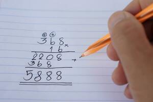 Handwriting with pen, numbers calculation with steps for multiple of  368x16 on paper in mathenatics subject. Concept, education. Calculation. Brain practice with numbers. photo