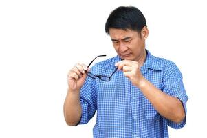 Asian man holds his eyeglasses to check because it not adjust focus with his eyesight. Concept , Eyesight health problem. Optometry. Glasses with convex or concave lenses. Myopia.Eye disease. photo