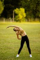 Pretty young woman stretching in the park photo