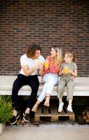 Family with a mother, father and daughter sitting outside on the steps of a front porch of a brick house photo