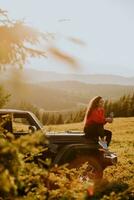 Young woman relaxing on a terrain vehicle hood at countryside photo