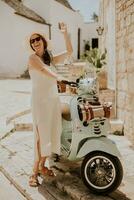 A young woman in a white dress and a white hat during tourist visit in Alberobello, Italy photo