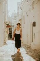 Female tourist with paper city map on narrow streets of Ostuni, Italy photo