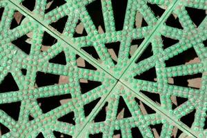 a green metal grate with holes in it photo