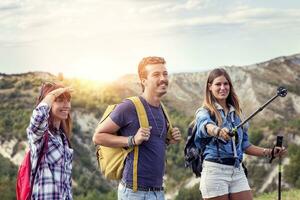 group of young hikers walking toward the horizon over the mountain photo