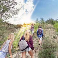 group of young hikers walking toward the horizon over the mountain photo