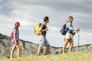 group of young hikers walking toward the horizon over the mountain photo