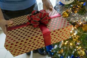 hermosa contento mujer a hogar en el Navidad atmósfera entre árbol y regalos foto