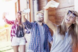 group of smiling friends in single file taking funny selfie with smart phone photo