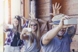 group of smiling friends in single file taking funny selfie with smart phone photo