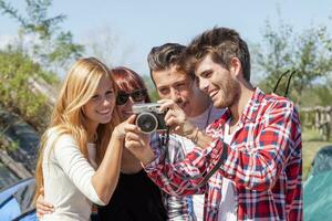 group of young adult watching photos on digital camera