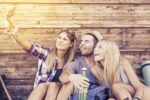 group of smiling friends taking funny selfie with smart phone photo