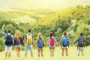 group of hikers in the mountain in single file holding hands photo