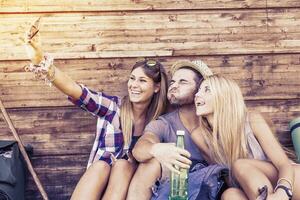 group of smiling friends taking funny selfie with smart phone photo