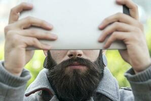 young hipster businessman holding the laptop in front of face photo