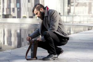 young hipster businessman consults his laptop in the heart of city photo