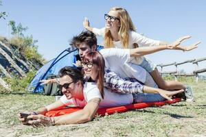 young boys and girls in campsite piled up smiling photo